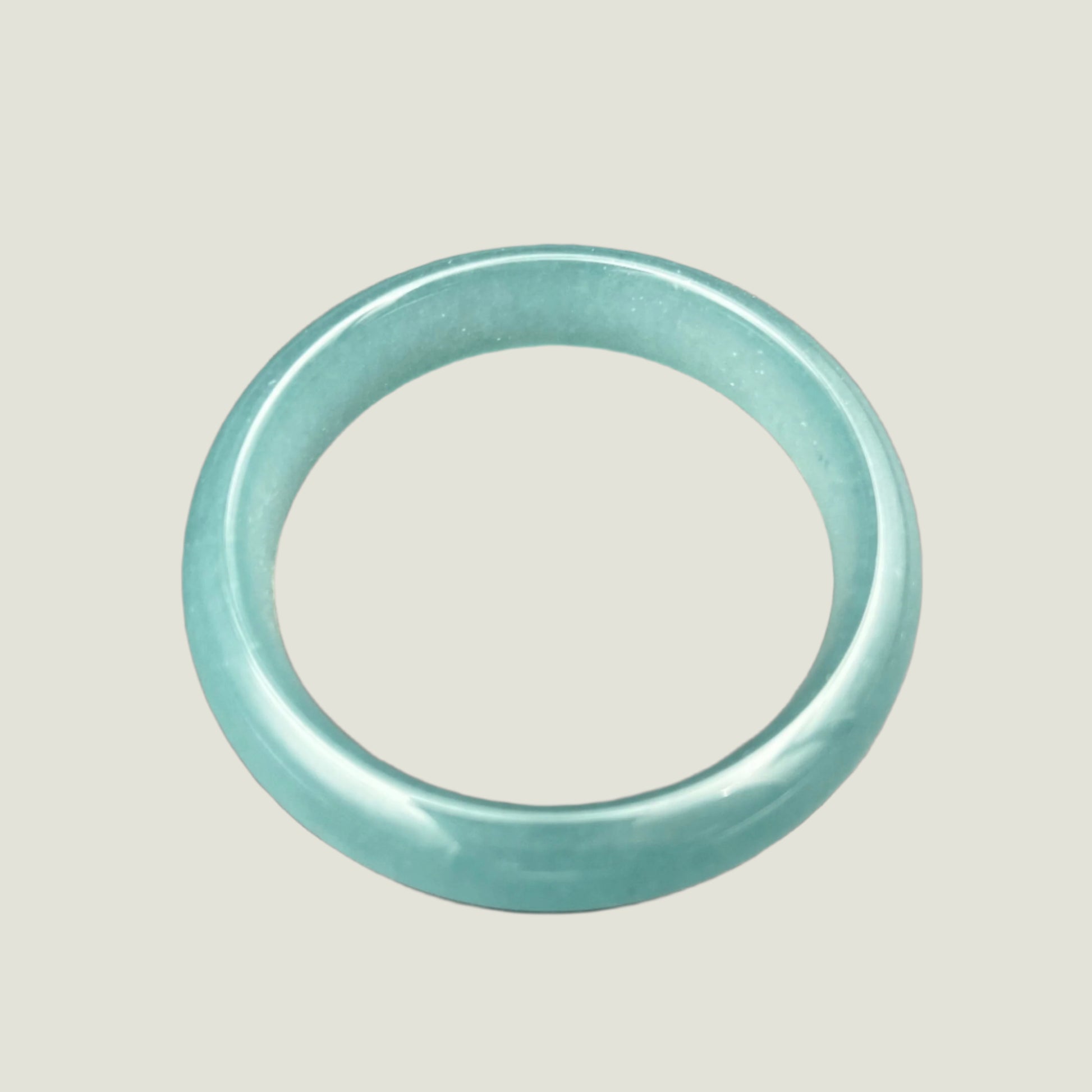 Teal jade ring on a gray background